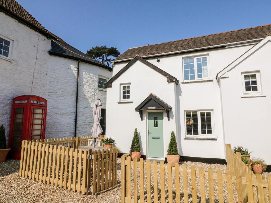 une maison blanche avec une porte rouge et une clôture dans l'établissement Swallow Cottage, à Ilfracombe