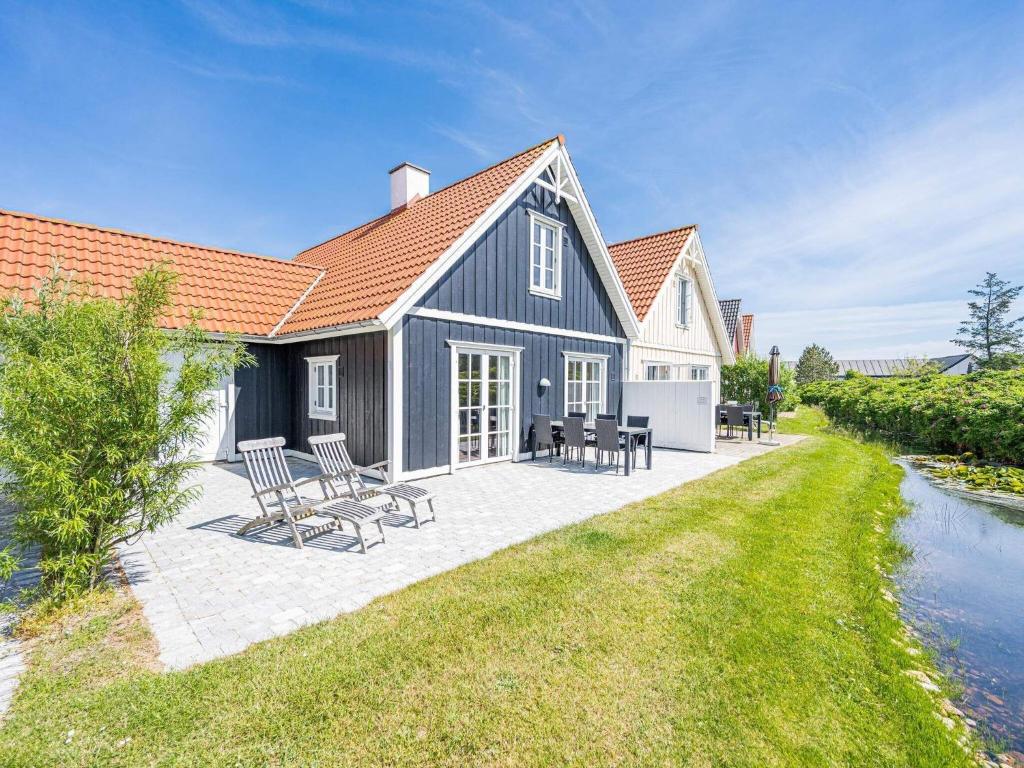 een huis met stoelen en een patio naast een rivier bij Holiday home Blåvand CXCVII in Blåvand