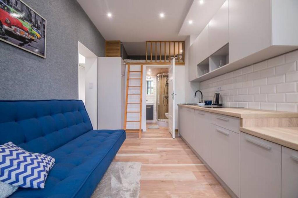 a living room with a blue couch in a kitchen at Seredyńskiego Gdańsk Studio Apartment in Gdańsk