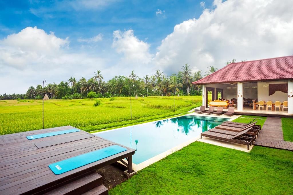 a villa with a swimming pool and a house at Champaca Luxury Villas Ubud in Ubud