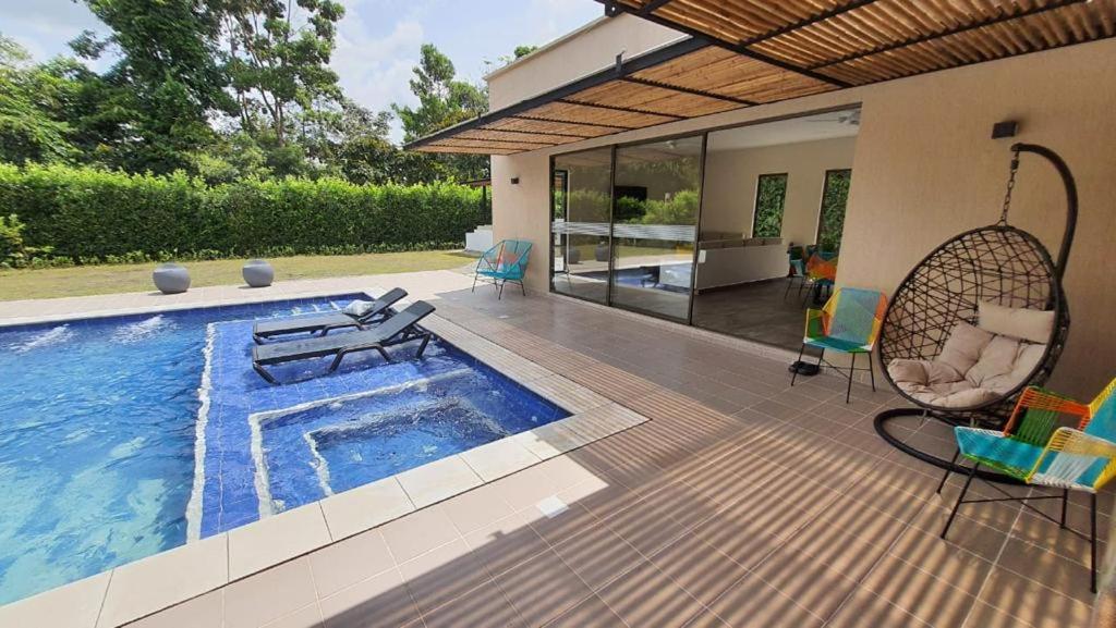 eine Terrasse mit einem Pool und Stühlen sowie ein Haus in der Unterkunft Finca los Colores in Villavicencio