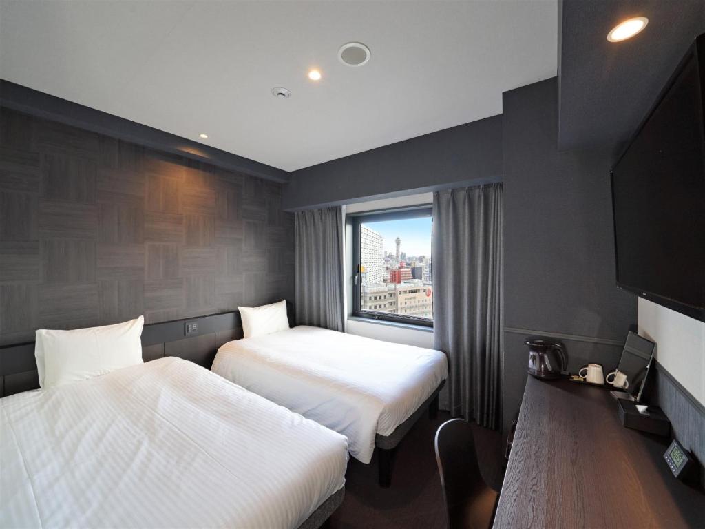 a hotel room with two beds and a window at CHISUN STANDARD Osaka Shin-Imamiya in Osaka