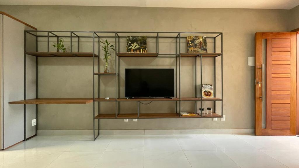 a living room with a tv on a wall with shelves at Loft amplo, apenas 6km do Morro do Careca! (G) in Natal