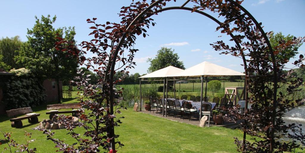 une arche avec une table et des chaises dans le jardin dans l'établissement Hotel Restaurant Gerwing-Wulf, à Alstätte