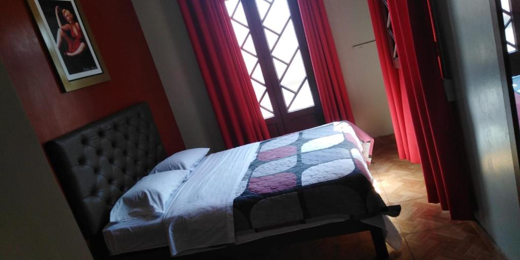 a bedroom with a bed and a window with red curtains at Anciejo inn ll in Lima