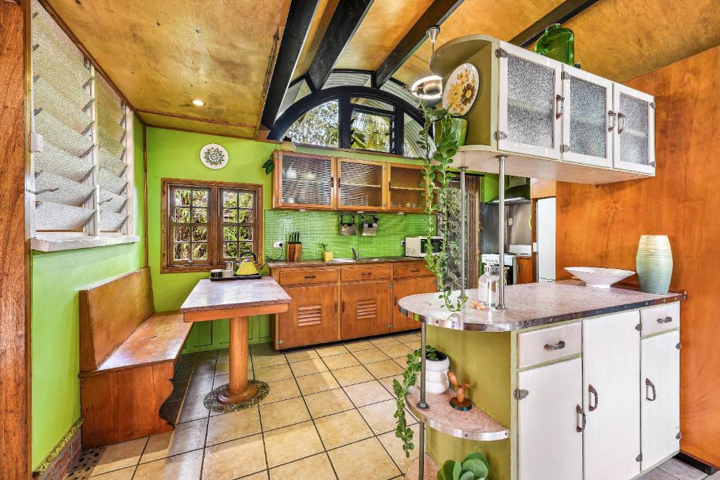 a kitchen with green walls and wooden cabinets at Cottonwood Cottage - Couples 'pet friendly' retro escape in Mudjimba