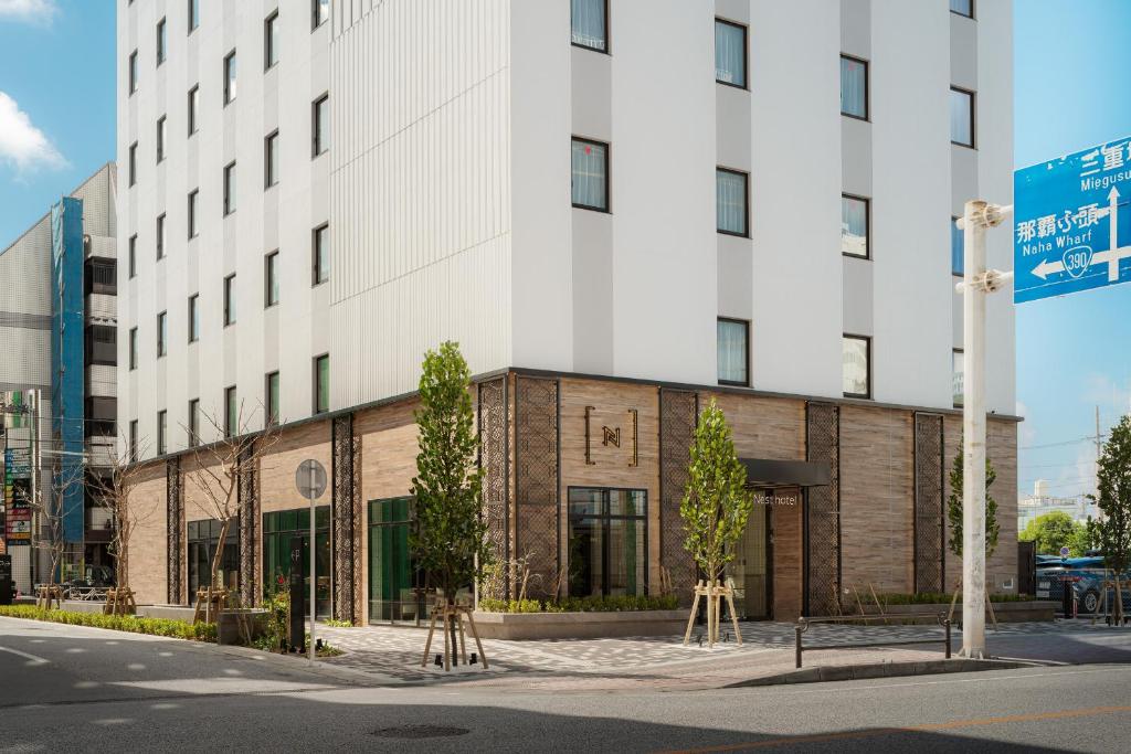 a white building with trees in front of it at Nest Hotel Naha Nishi in Naha