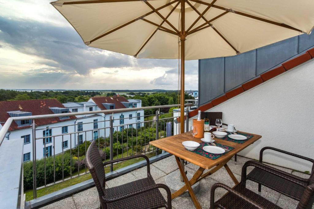 een tafel en stoelen op een balkon met een parasol bij Residenz Bellevue Fewo 30 Fewo cc Herrmann in Zinnowitz