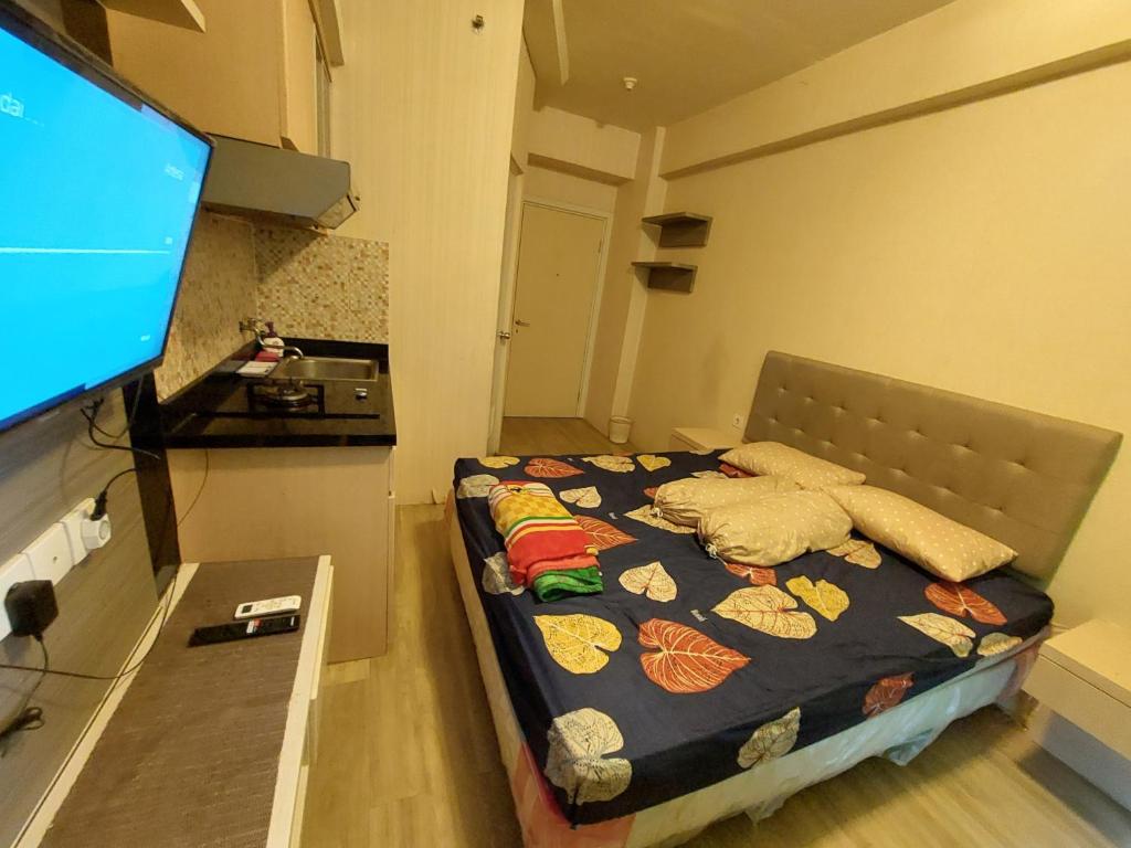 Il comprend une petite chambre avec un lit et une télévision à écran plat. dans l'établissement Green Pramuka Apartement By Vici, à Jakarta