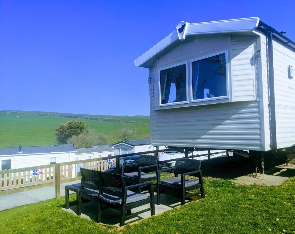 a tiny house sitting on a deck with chairs at 4 Berth Couples and Family Caravan in Beautiful Newquay Bay Resort in Newquay