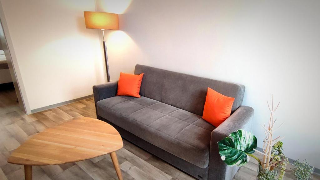 sala de estar con sofá gris y almohadas de color naranja en Ferienwohnung am Birkenwäldchen en Plauen
