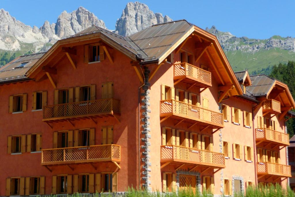 a large red building with mountains in the background at Lumen in Falcade