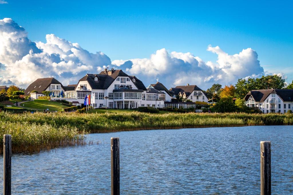una fila de casas en la orilla de un cuerpo de agua en Balmer See – Hotel•Golf•Spa en Balm