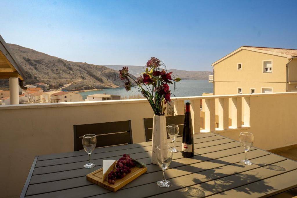 una mesa con copas de vino y flores en el balcón en Modern Oceanview, en Metajna