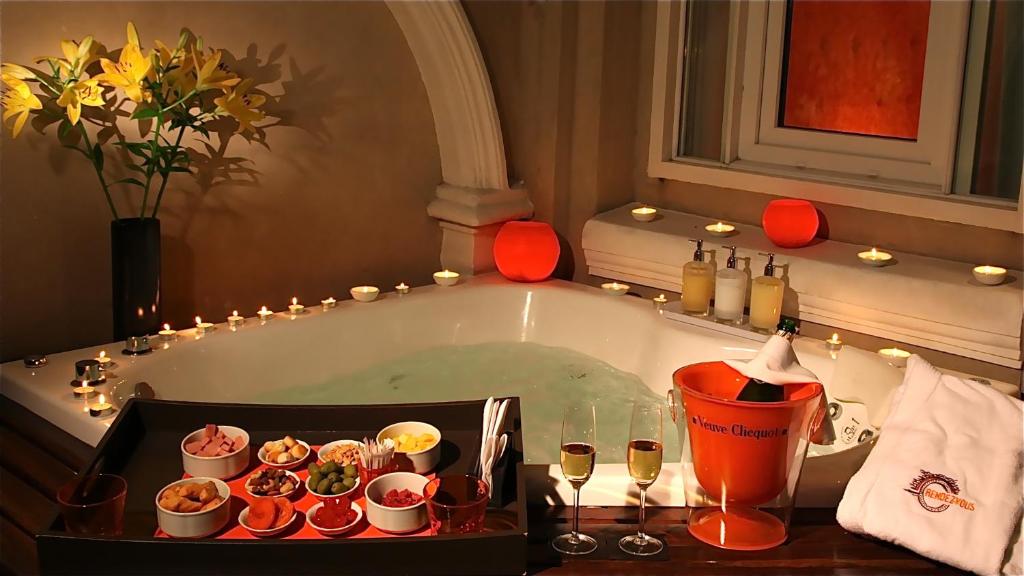 a bath tub with a tray of food and glasses of wine at Rendez Vous Hotel Buenos Aires in Buenos Aires