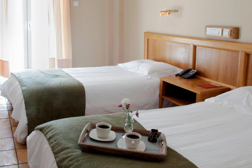 Habitación de hotel con 2 camas, tazas de café y bandeja. en Pella, en Tesalónica