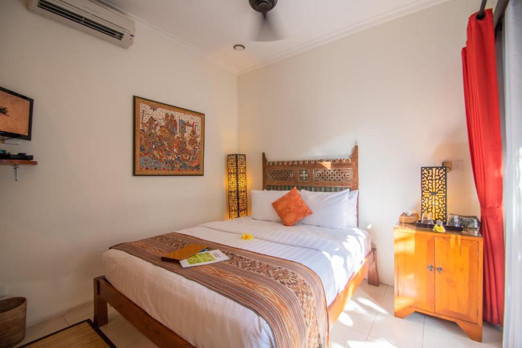 a bedroom with a bed and a dresser in it at Kembali Lagi Guest House in Sanur