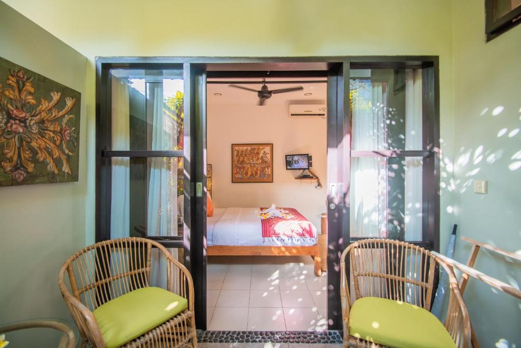 a room with a bedroom with a bed and two chairs at Kembali Lagi Guest House in Sanur
