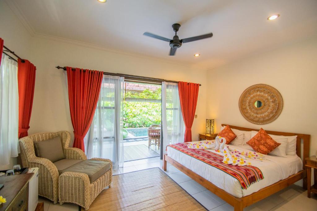 a bedroom with a bed and a chair and a window at Kembali Lagi Guest House in Sanur