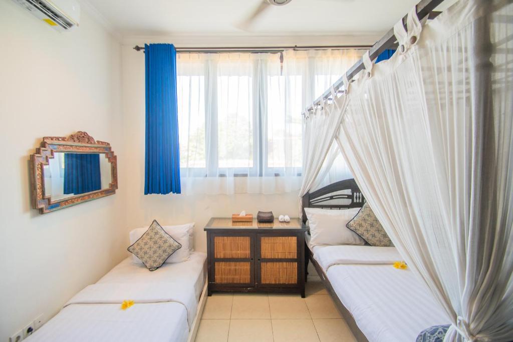 two beds in a room with a window at Kembali Lagi Guest House in Sanur