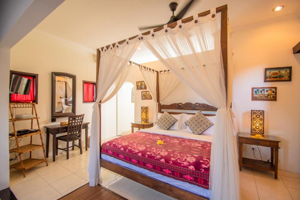a bedroom with a canopy bed and a table at Kembali Lagi Guest House in Sanur