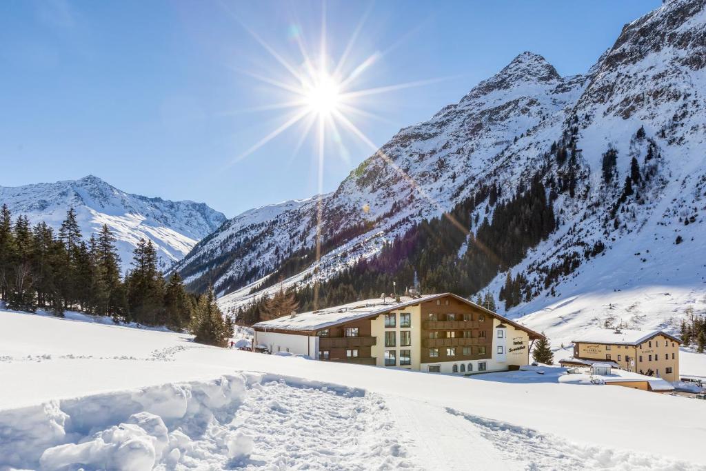 um edifício na neve com montanhas ao fundo em Hotel Sonnblick em Sankt Leonhard im Pitztal