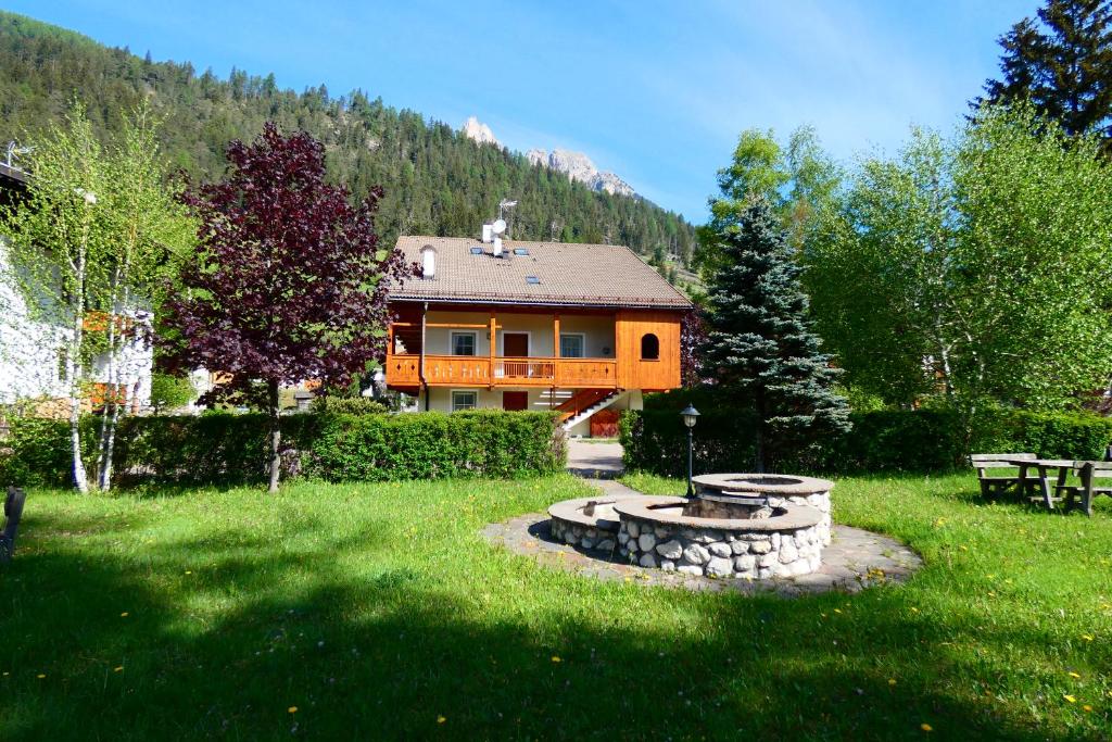 una casa in mezzo a un cortile con una panchina di Casa El Tobià a Pozza di Fassa