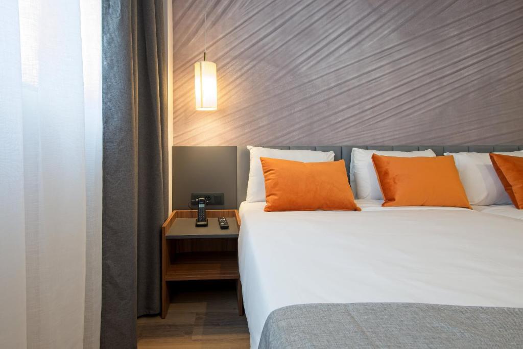 a bedroom with a large bed with orange pillows at DWO Yuste Alcalá in Madrid