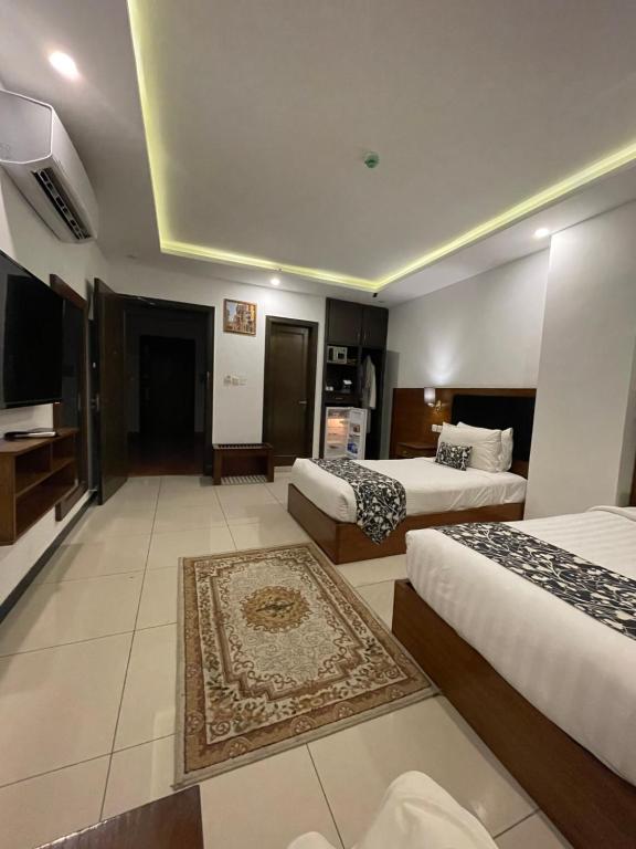 a hotel room with two beds and a flat screen tv at Grand Mongolia Hotel in Rawalpindi