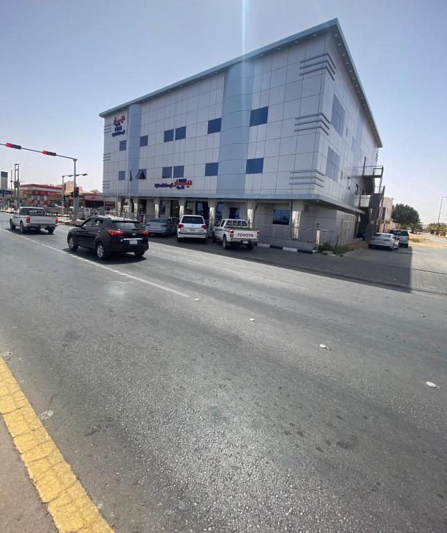 ein Gebäude, in dem Autos an der Straßenseite geparkt sind in der Unterkunft ديار الأحبة للوحدات السكنية المفروشة in Sakaka