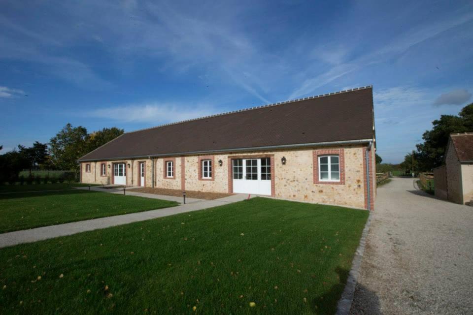 ein großes Backsteingebäude mit einem großen Rasenplatz in der Unterkunft Le parc de Crécy in Crécy-Couvé