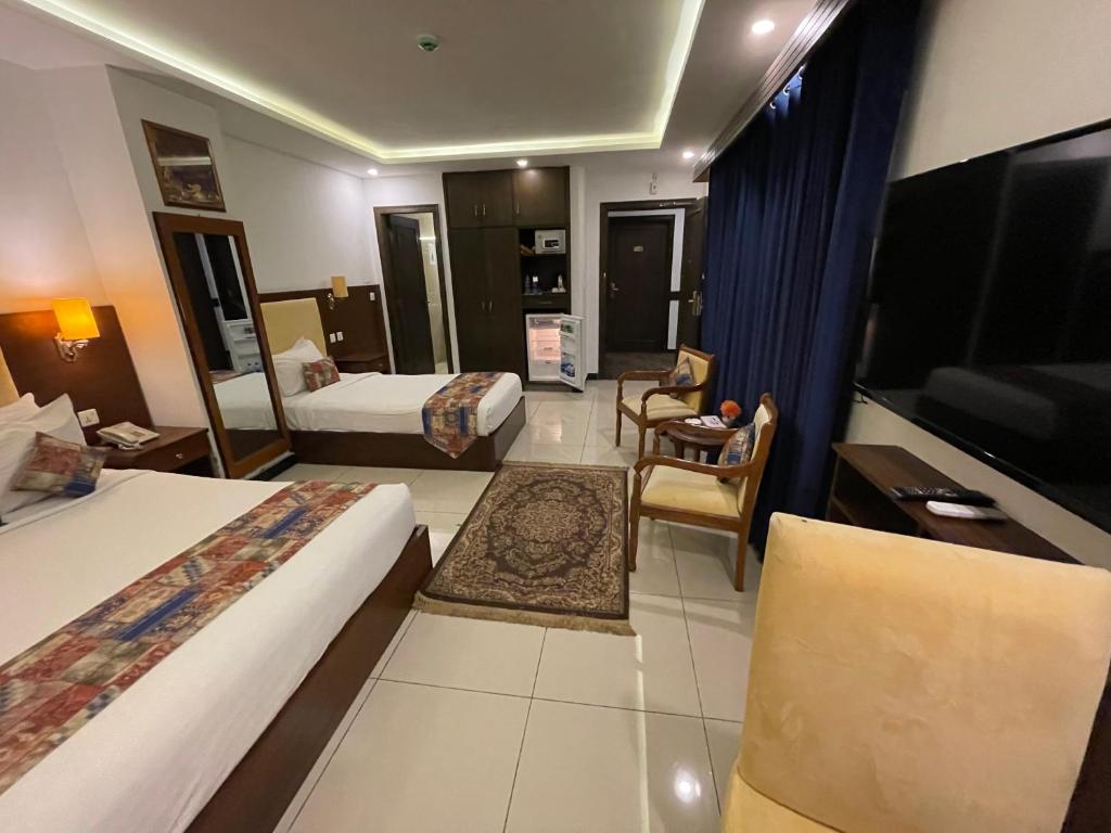 a hotel room with two beds and a television at Grand Mongolia Hotel in Rawalpindi