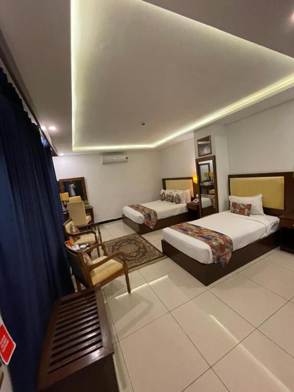 a hotel room with two beds and a chair at Grand Mongolia Hotel in Rawalpindi