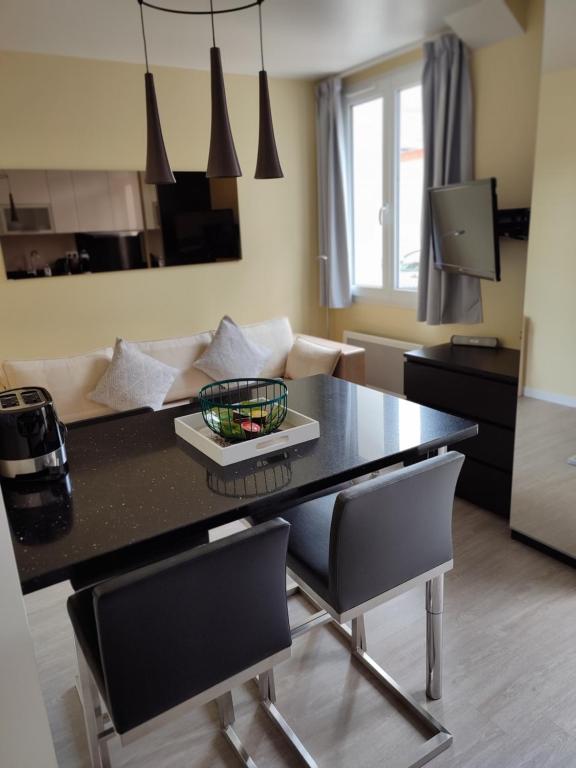 uma cozinha e sala de estar com uma mesa preta e cadeiras em Appartement avec terrasse - M4 Lucie Aubrac em Bagneux
