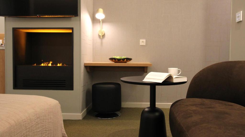 a room with a fireplace and a table with a book at MiHotel Sala in Lyon