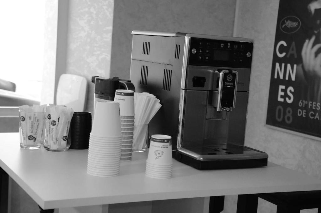a counter with a coffee maker and cups on a table at Hotel des Congrès et Festivals in Cannes