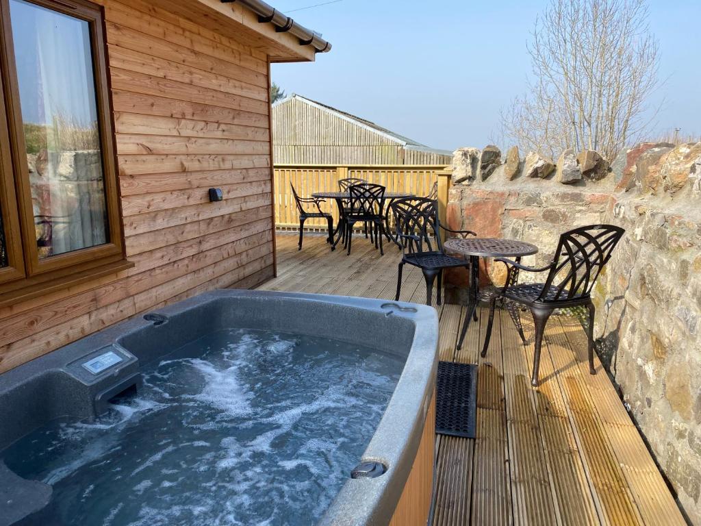 a hot tub on a deck with a table and chairs at Partridge Lodge with Hot Tub in Forgandenny