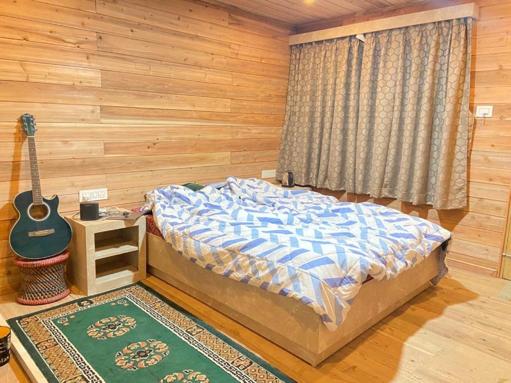 ダージリンにあるNorbu Thungkar Homestayのベッドルーム1室(ベッド1台、ギター付)