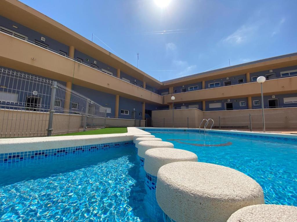 a swimming pool in front of a building at Apartamentos Playamar in Isla Plana