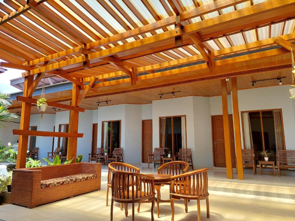 un patio con pérgola de madera, mesa y sillas en OASIS HOTEL en Ampana