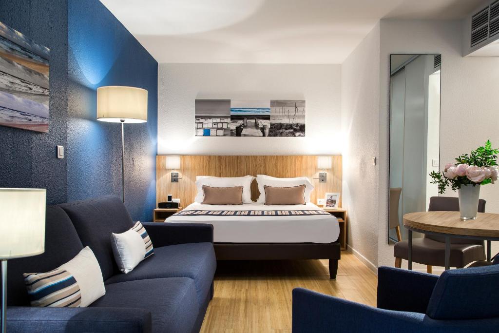 une chambre d'hôtel avec un lit et un canapé dans l'établissement Citadines Croisette Cannes, à Cannes