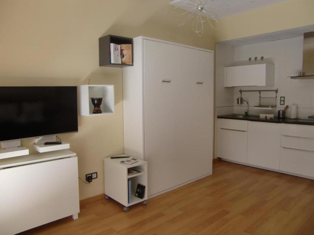 a kitchen with white cabinets and a flat screen tv at Estudio Centro histórico in Málaga