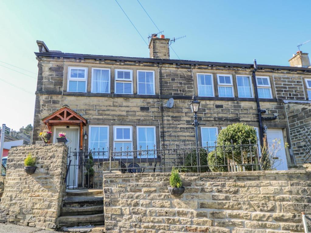 an old stone house with a stone staircase in front of it at Ducking Well Cottage in Keighley