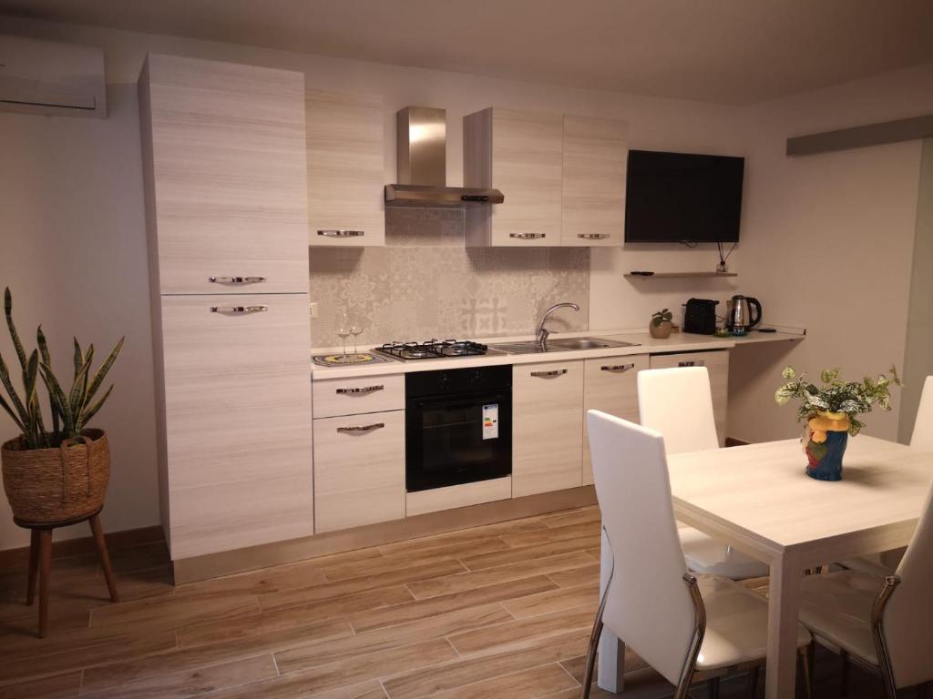 kuchnia z białymi szafkami i stołem z krzesłami w obiekcie Casa dei Tre Re w mieście Palermo