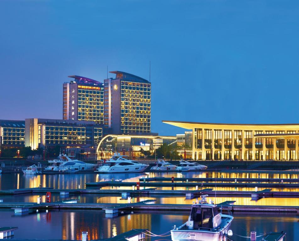 een groep boten aangemeerd in een haven met gebouwen bij InterContinental Qingdao, an IHG Hotel - Inside the Olympic Sailing Center in Qingdao