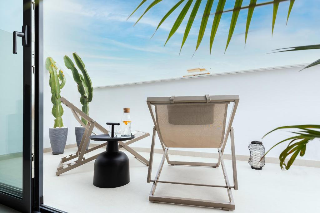 een stoel en een tafel op een balkon met een cactus bij Caleyro Boutique Apartments - "Parking incluido" in Fuengirola
