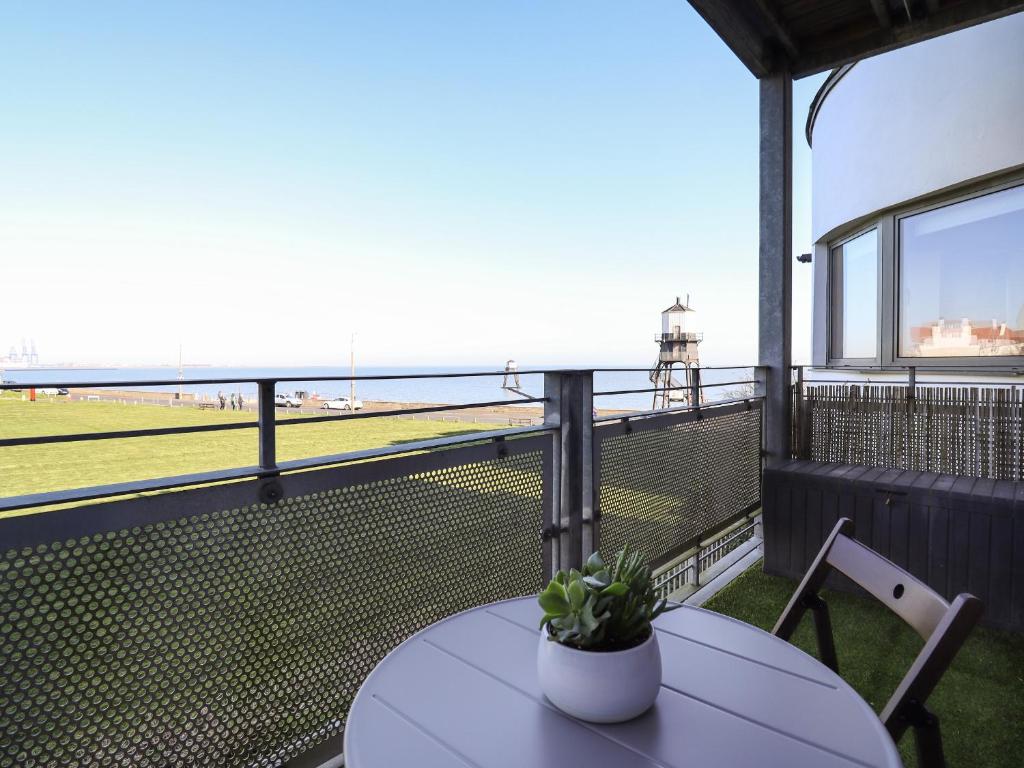 a table and chairs on a balcony with a tennis court at Flat 19 By The Beach in Harwich