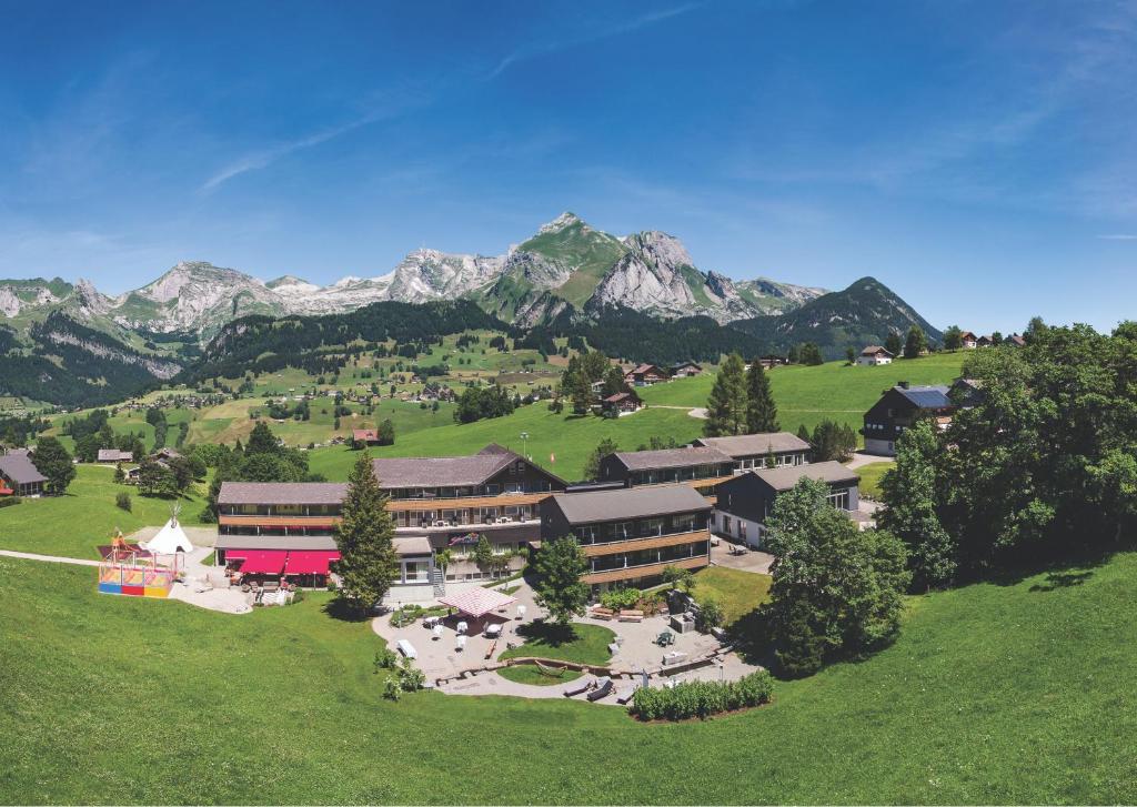 a large building on a hill with mountains in the background at Hotel Stump's Alpenrose in Wildhaus