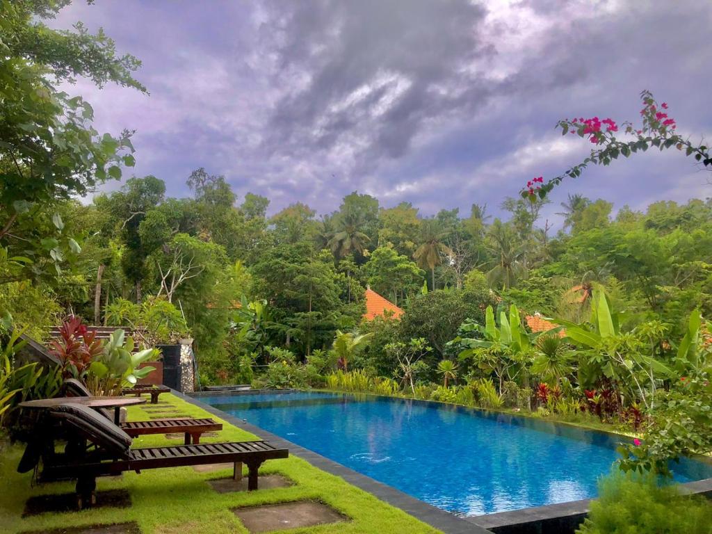 a swimming pool in the middle of a garden with trees at Arya Resort Nusa Penida in Nusa Penida