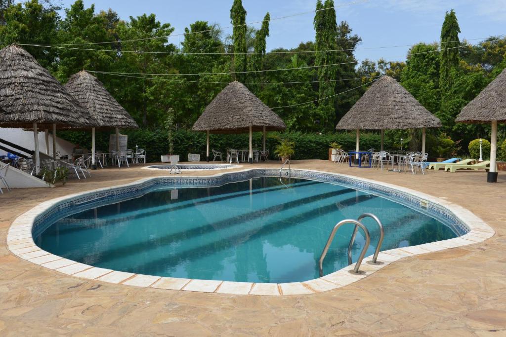 Morogoro Hotel في Morogoro: مسبح مع كراسي ومظلات في المنتجع